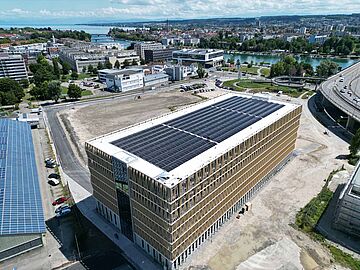 Luftaufnahme eines Gebäudes mit Solaranlage in städtischer Umgebung nahe eines Flusses